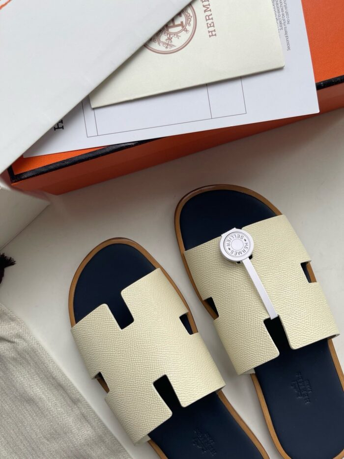 Sandali moderni di lusso con design elegante, dettaglio H e packaging premium sofisticato.