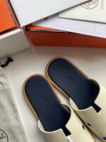 Sandali minimalisti di lusso con suola blu e confezione elegante in stile moderno.