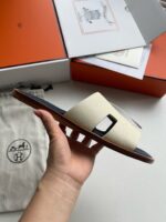 Sandalo minimalista crema con dettaglio moderno, presentato in mano, elegante e di alta qualità.