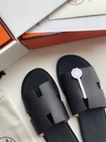 Sandali neri di lusso con logo elegante e confezione premium in stile minimalista.