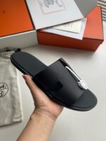 Sandali neri di lusso minimalisti con logo circolare e design elegante per look casual sofisticato.