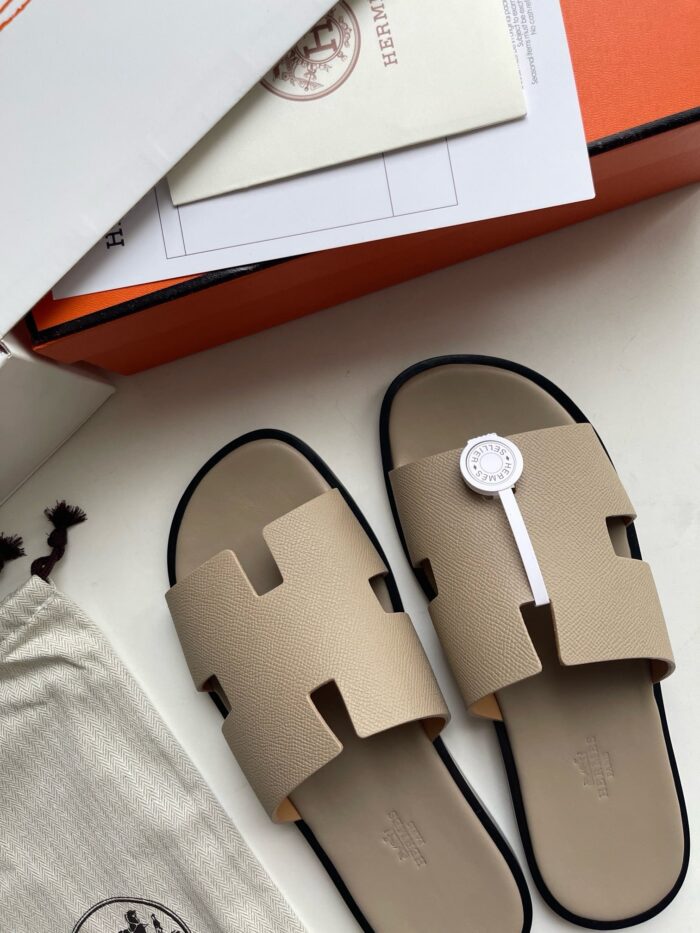 Sandali eleganti beige con cinturino H, in fondo una scatola di lusso e dust bag.