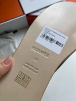 Suola elegante Hermès con marchio, codice a barre e packaging di lusso.