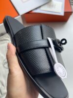 Sandalo nero di lusso con strap in textured, design moderno e dettaglio brand elegante.