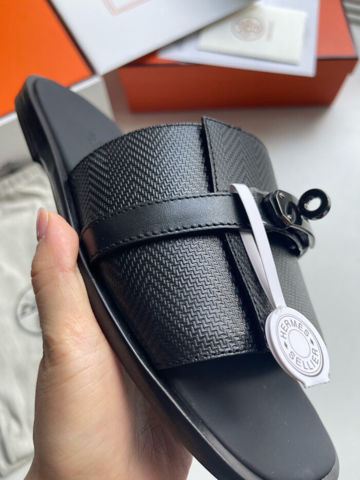 Sandalo nero di lusso con strap in textured, design moderno e dettaglio brand elegante.