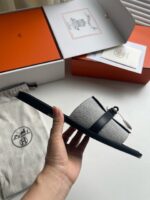 Sandalo minimalista grigio con cinturino nero, packaging premium e finiture eleganti.