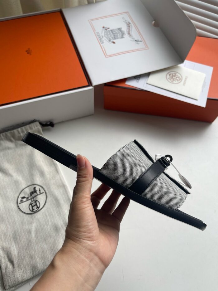 Sandalo minimalista grigio con cinturino nero, packaging premium e finiture eleganti.