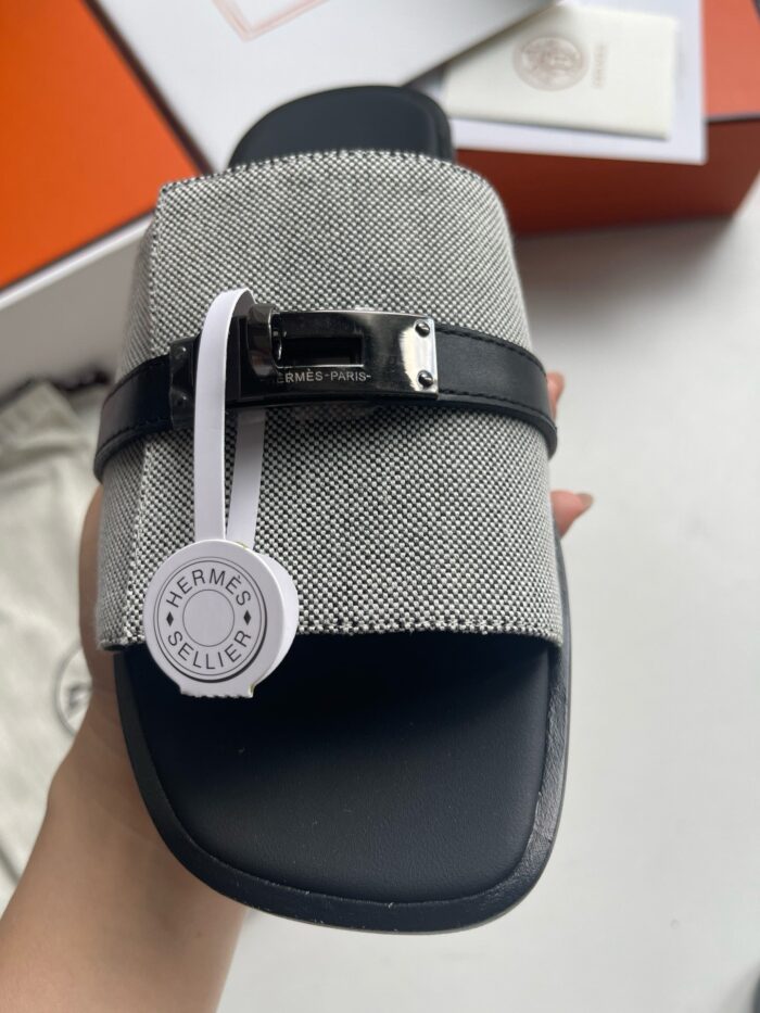 Sandalo uomo elegante con cinturino in metallo, tessuto grigio e dettaglio raffinato.