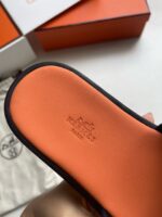 Sandalo di lusso con suola arancione e logo embossato, elegante e dettagliato.