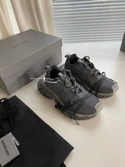 Sneakers grigie moderne con dettagli riflettenti, borsa nera elegante, stile e comfort raffinati.