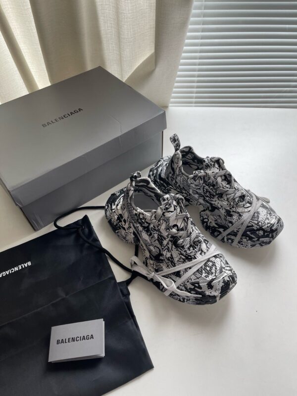 Sneakers Balenciaga di lusso con scatola e dust bag su superficie bianca elegante.