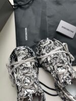 Scarpe Balenciaga nere e bianche con design artistico e dust bag elegante.