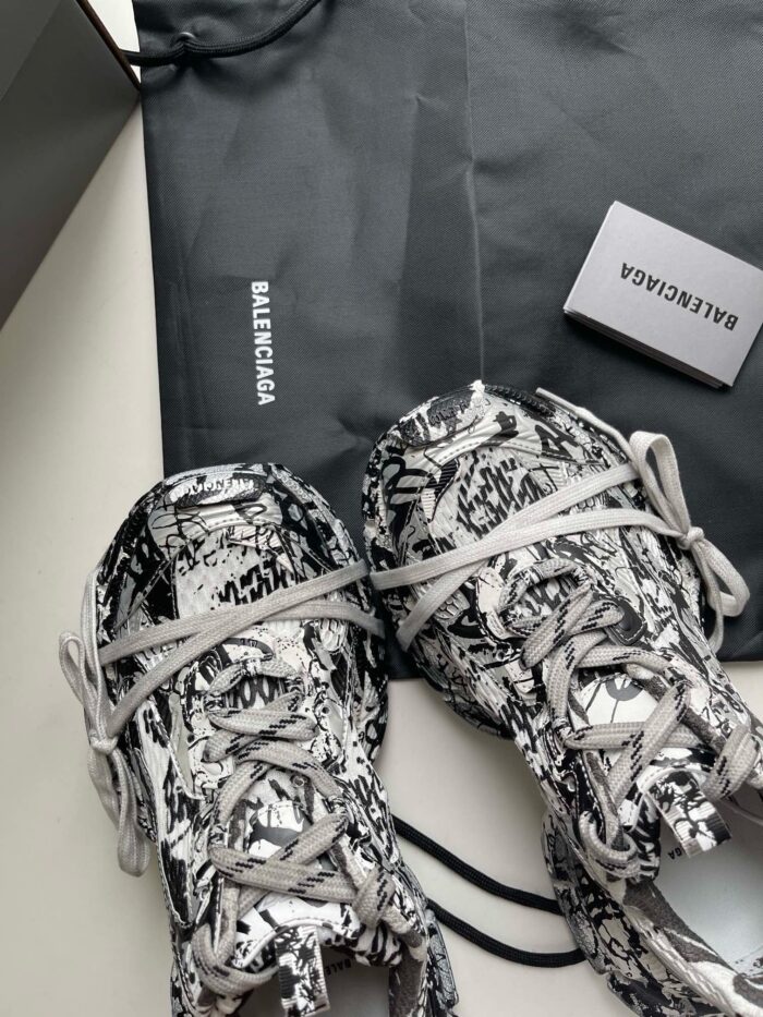Scarpe Balenciaga nere e bianche con design artistico e dust bag elegante.