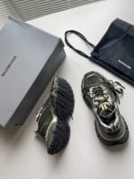 Sneakers Balenciaga moderne con scatola e accessori di lusso su sfondo bianco.