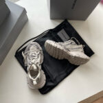 Sneakers moderne bianche con dettagli eleganti su borsa nera, stile casual e di tendenza.