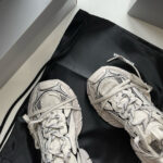 Scarpe sportive moderne bianche su borsa nera elegante, stile minimalista e design di lusso.