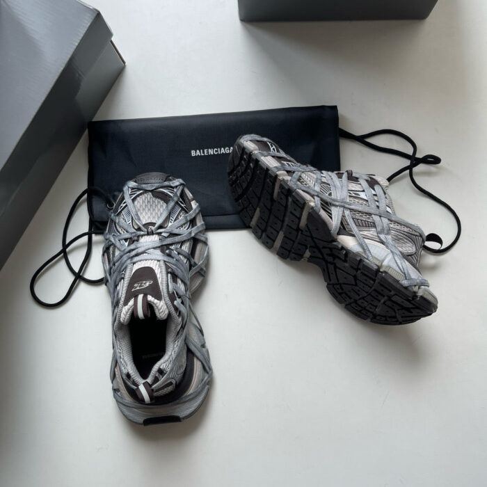 Sneakers Balenciaga grigie con dettagli moderni e sacchetto in stile streetwear.