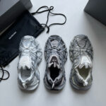 Sneakers moderne in grigio e bianco con design futuristico e materiali innovativi.