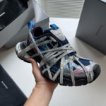 Scarpa sneaker moderna con fasce elastiche bianche e design innovativo, dettaglio di stile unico.
