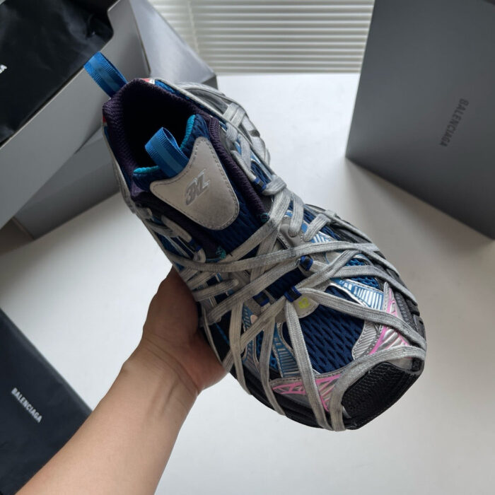 Sneaker sportiva moderna blu, rosa e grigia con design innovativo e dettagli respiranti.