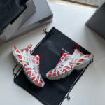 Sneakers rosse e bianche, elegante borsa nera, packaging premium, stile sportivo e moderno.