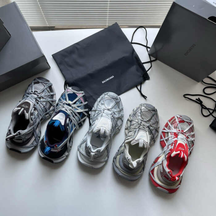 Scarpette sneakers di diversi stili e colori con scatole nere e borsa in esposizione elegante.