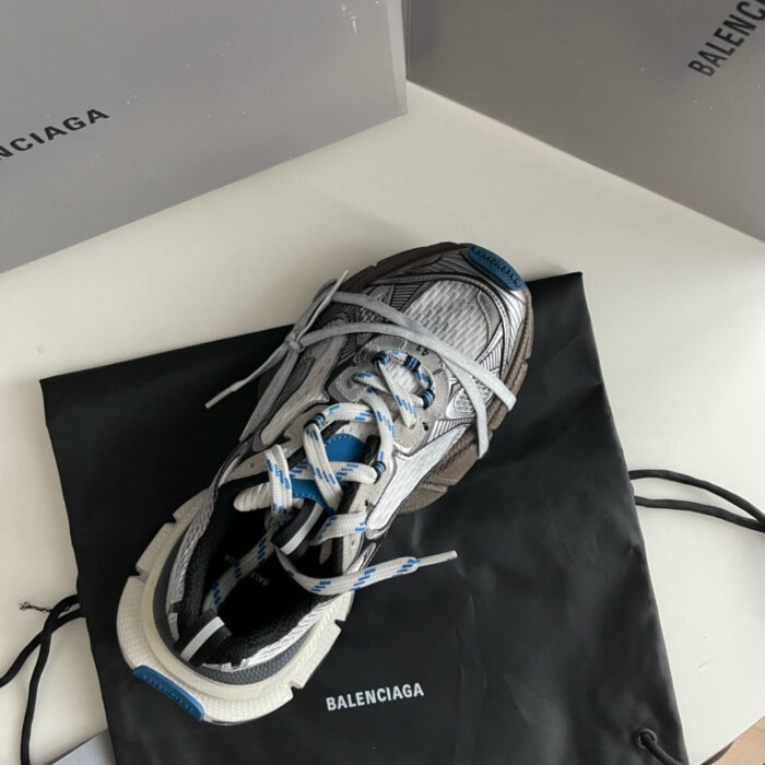 Sneaker Balenciaga futuristica su sacco nero, con borse di lusso sullo sfondo.