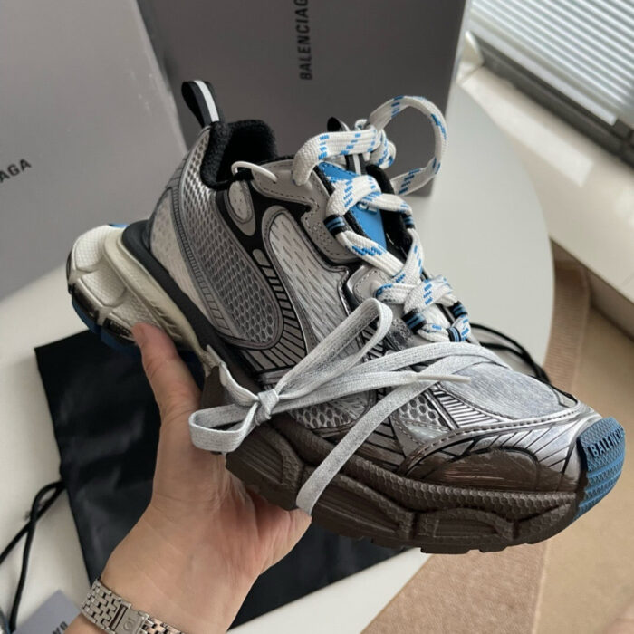 Sneaker Balenciaga grigia con dettagli blu e design elegante, perfetta per look trendy e sofisticati.