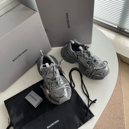 Sneakers Balenciaga grigie di lusso con scatole e dust bag, stile moderno e elegante.
