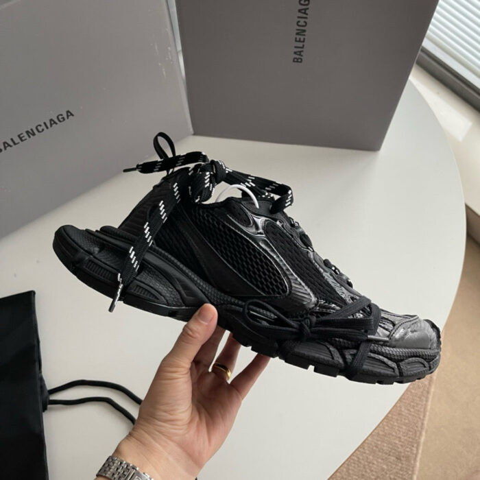 Sneaker Balenciaga nera di lusso con design moderno, tenuta in mano, con scatola signature elegante.