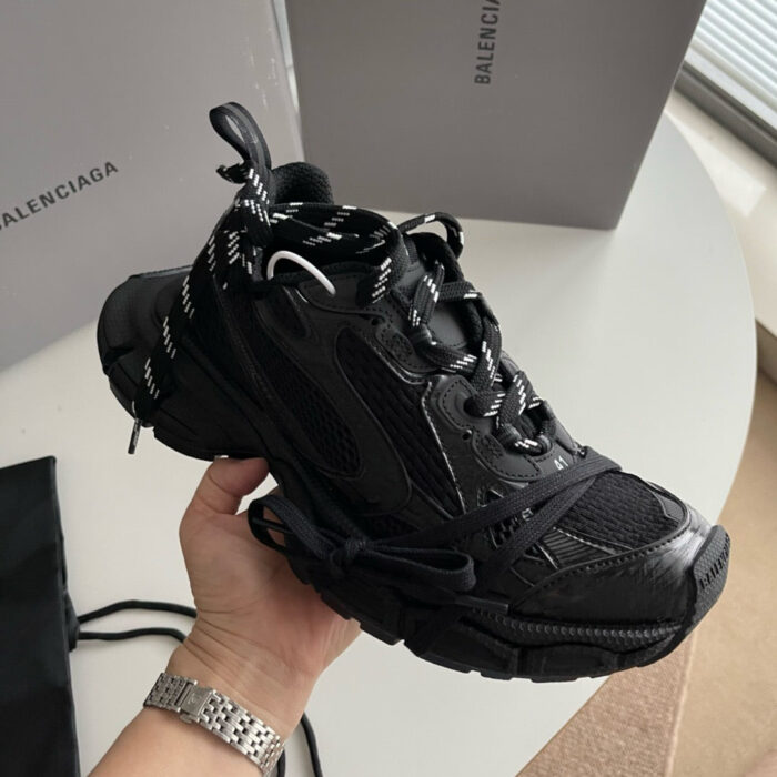Sneaker Balenciaga nera con lacci bianchi, suola robusta e design moderno e lussuoso.