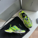 Sneaker Balenciaga Triple S verde fluo con scatole di design e borsa luxury.