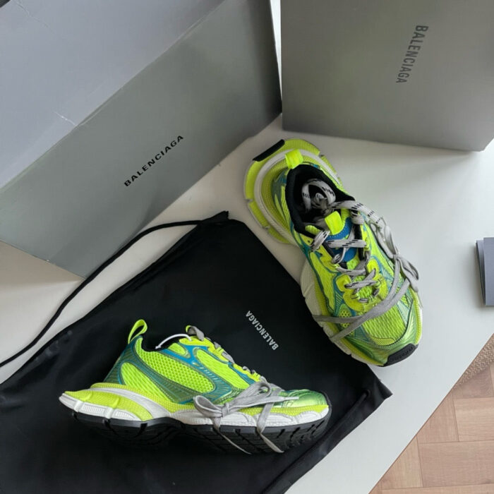 Sneaker Balenciaga Triple S verde fluo con scatole di design e borsa luxury.