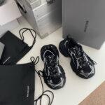 Sneakers di lusso nere con dettagli bianchi, accessori e confezioni eleganti in stile streetwear moderno.