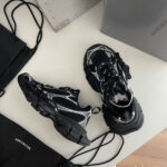 Sneaker chunky nera con borse minimaliste in stile urbano su superficie bianca sofisticata.