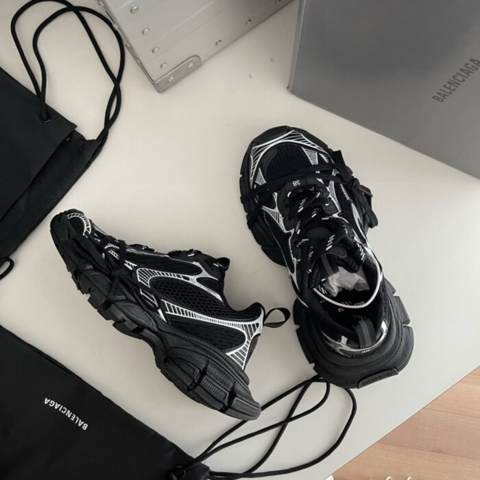 Sneaker chunky nera con borse minimaliste in stile urbano su superficie bianca sofisticata.