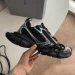 Sneaker futuristica nera e bianca con suola robusta, design innovativo e comfort massimo.