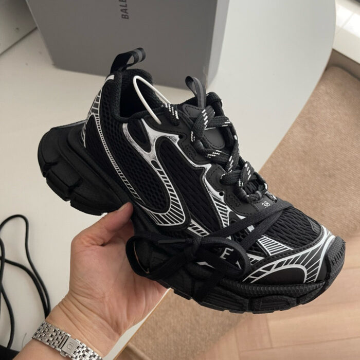 Sneaker nera moderna con dettagli grafici, suola spessa e design urbano trendy.