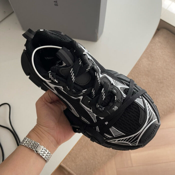 Sneaker sportiva nera con dettagli bianchi, suola robusta e design dinamico, in ambiente interno.