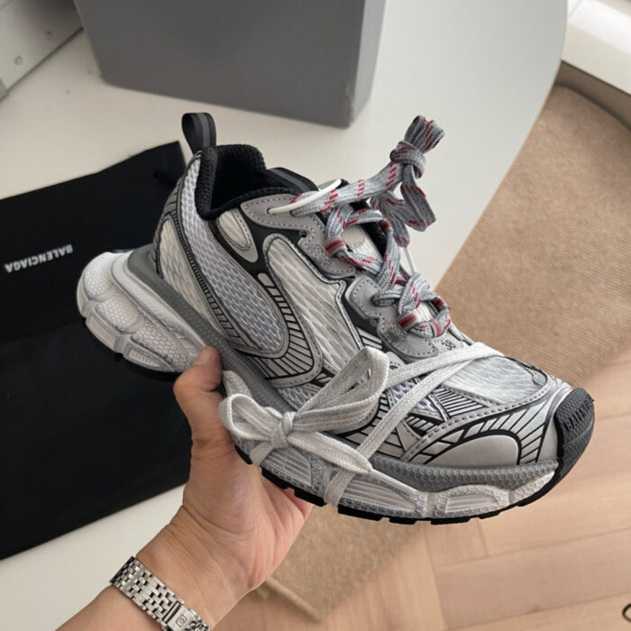 Sneaker sportiva moderna grigia e bianca con dettagli rossi e neri, comoda e di stile.