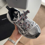 Sneaker moderna grigia con lacci rossi, design sportivo e stile minimalista in interno elegante.