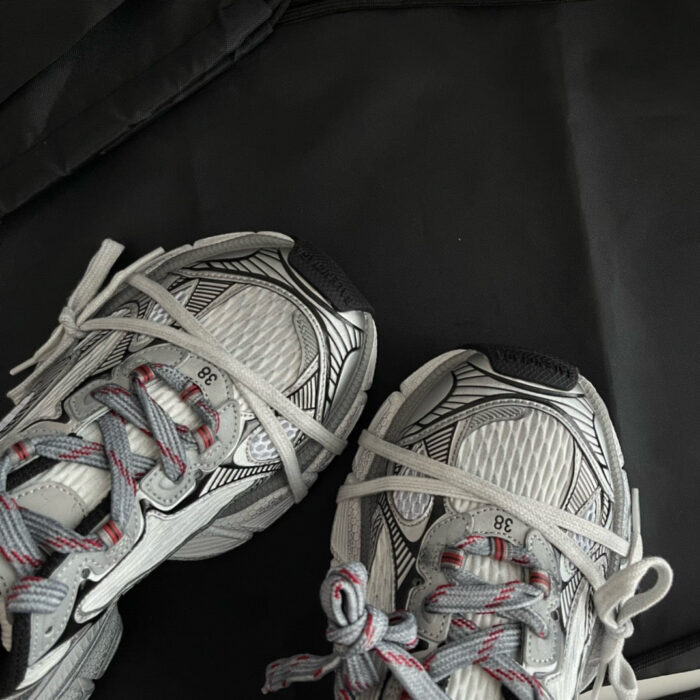 Scarpe sportive grigie con dettagli rossi, materiali leggeri e riflessi per allenamento e stile.
