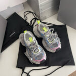 Scarpe sportive grigie con dettagli neon, accompagnate da eleganti borse di trasporto moderne.