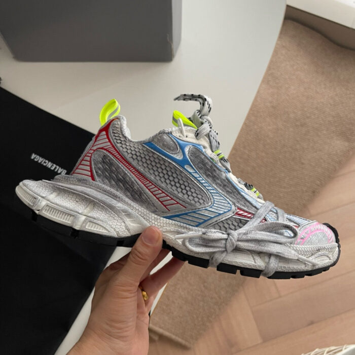 Sneaker moderna in mesh e sintetico con dettagli riflettenti e accenti colorati, ideale per sport e stile urbano.