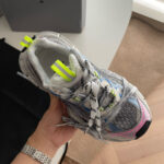 Sneaker da corsa grigia con dettagli neon, supporto stabile e design moderno per performance e stile.
