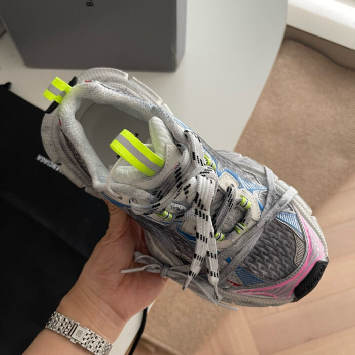 Sneaker da corsa grigia con dettagli neon, supporto stabile e design moderno per performance e stile.
