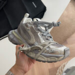 Sneaker futuristica in argento con lacci asimmetrici e design moderno per stile e comfort sportivo.