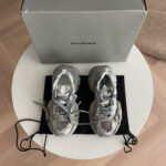 Sneakers Balenciaga grigie di lusso su tavolo bianco con confezione e dust bag elegante