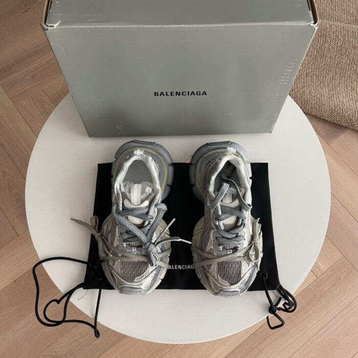 Sneakers Balenciaga grigie di lusso su tavolo bianco con confezione e dust bag elegante