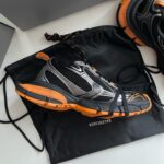 Scarpe sportive Balenciaga nere e arancioni con borsa di lusso, stile moderno e performance.
